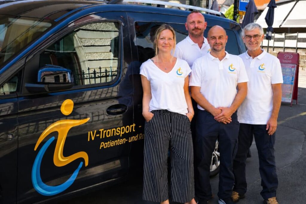Team von IV Transport vor einem modernen Transportfahrzeug für Patienten- und Rollstuhltransporte